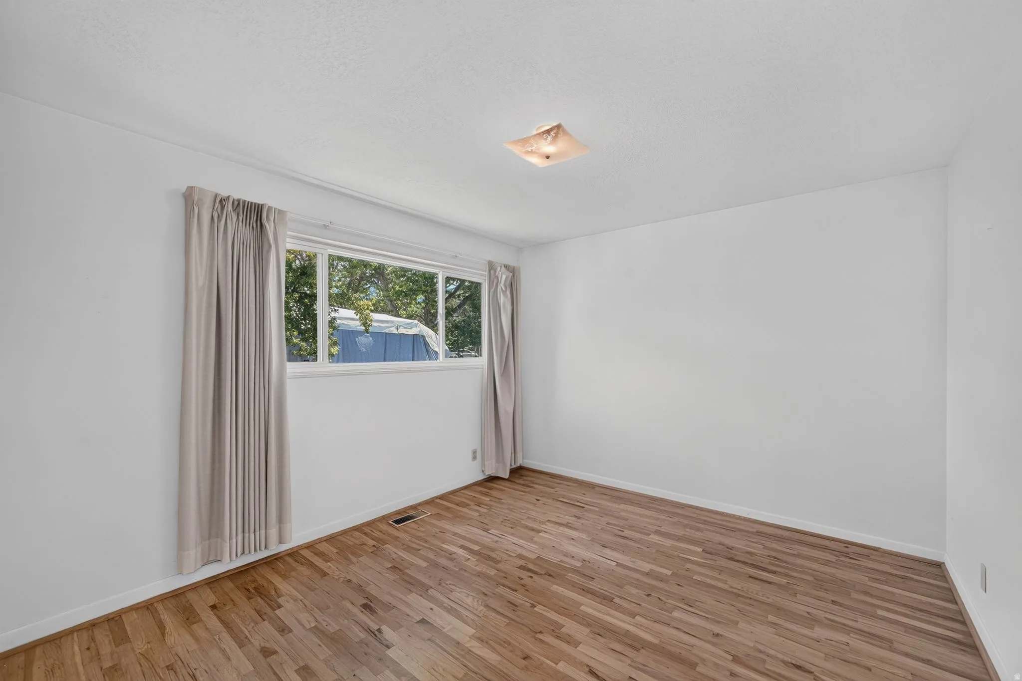 Room featuring wood-finish flooring, white walls, and a multi-pane window