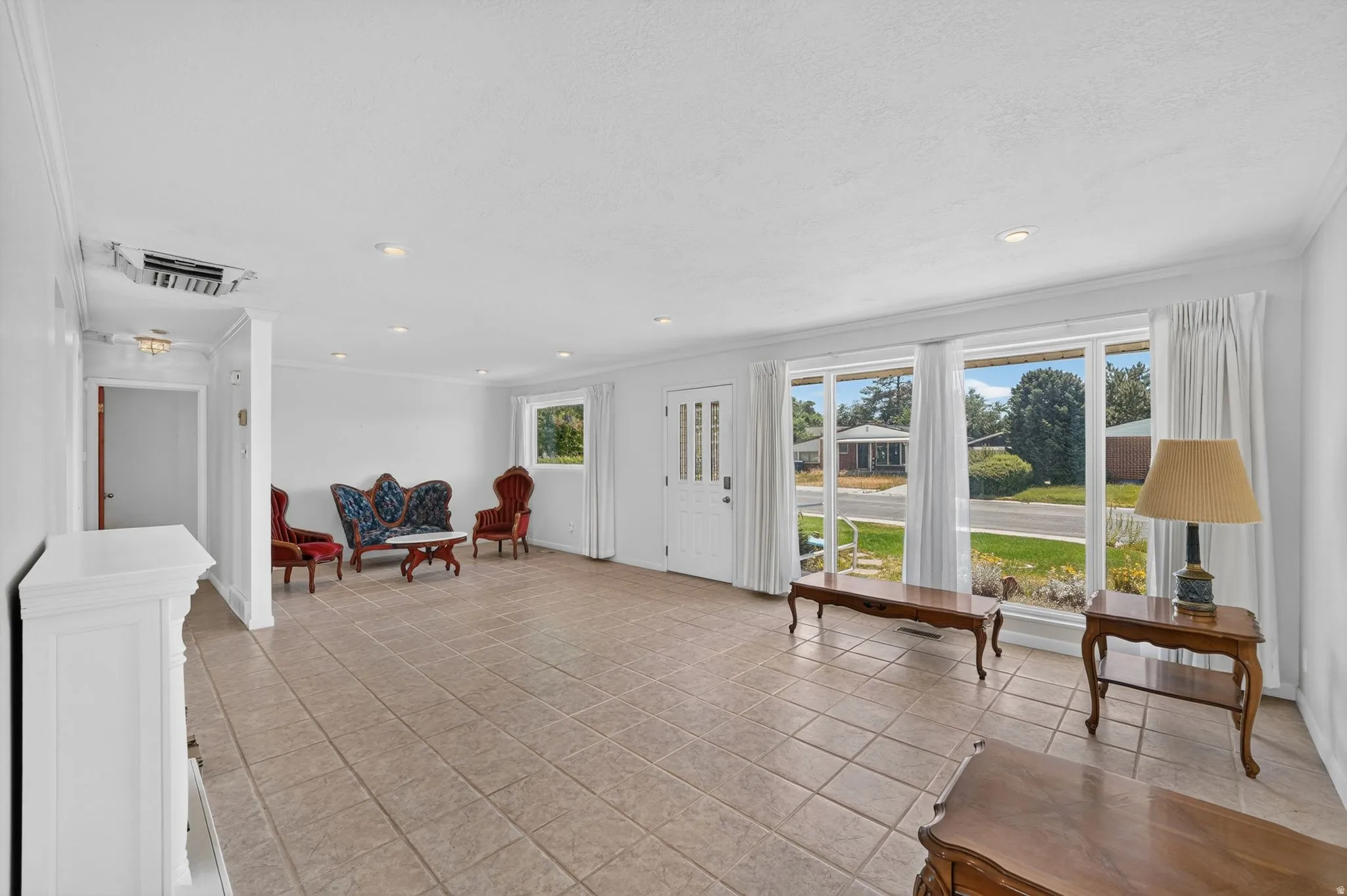 Spacious room featuring neutral tile flooring, recessed lighting, and crown molding