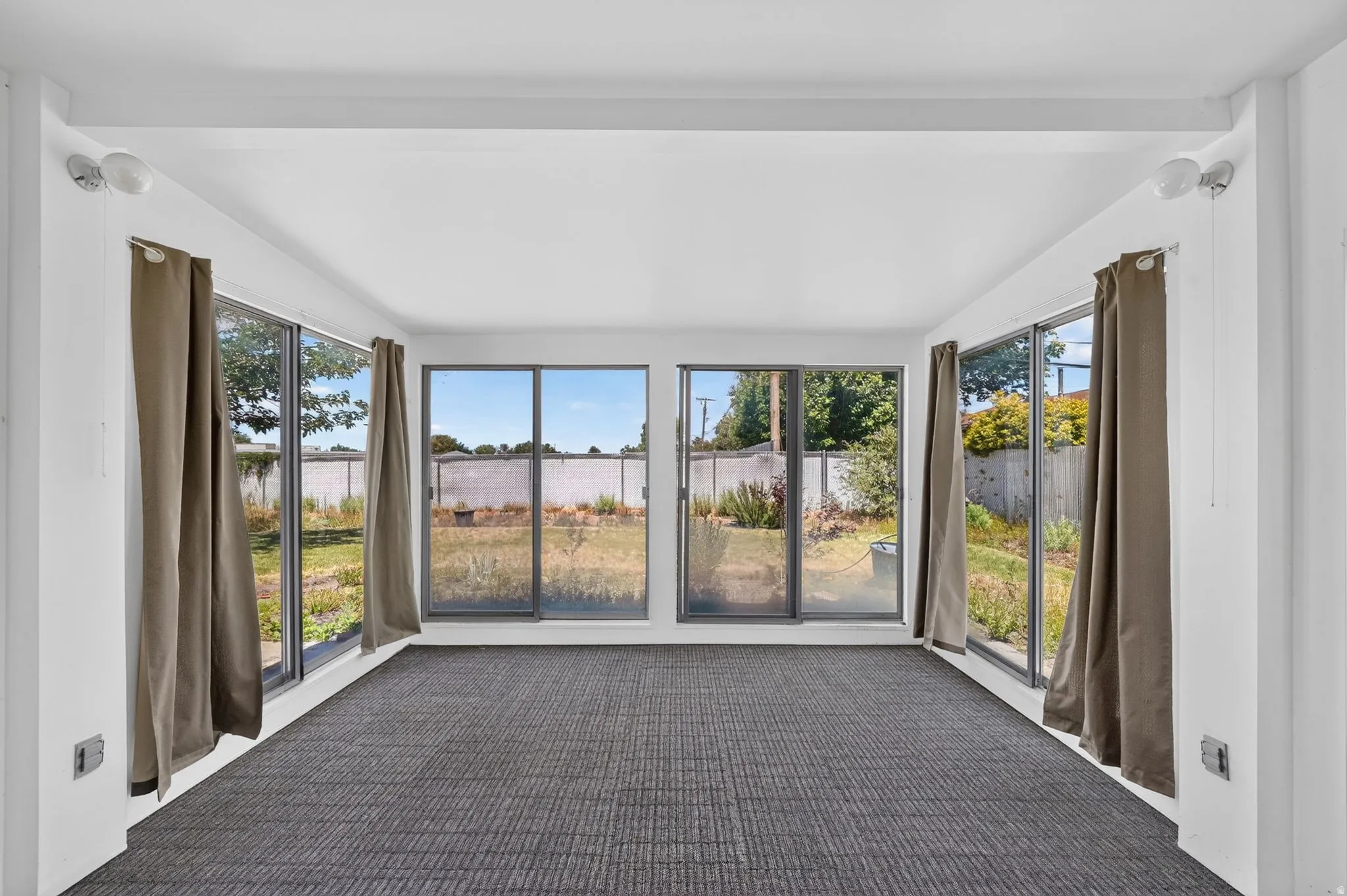 Sunroom featuring extensive window-lines, white painted walls, and textured carpet flooring