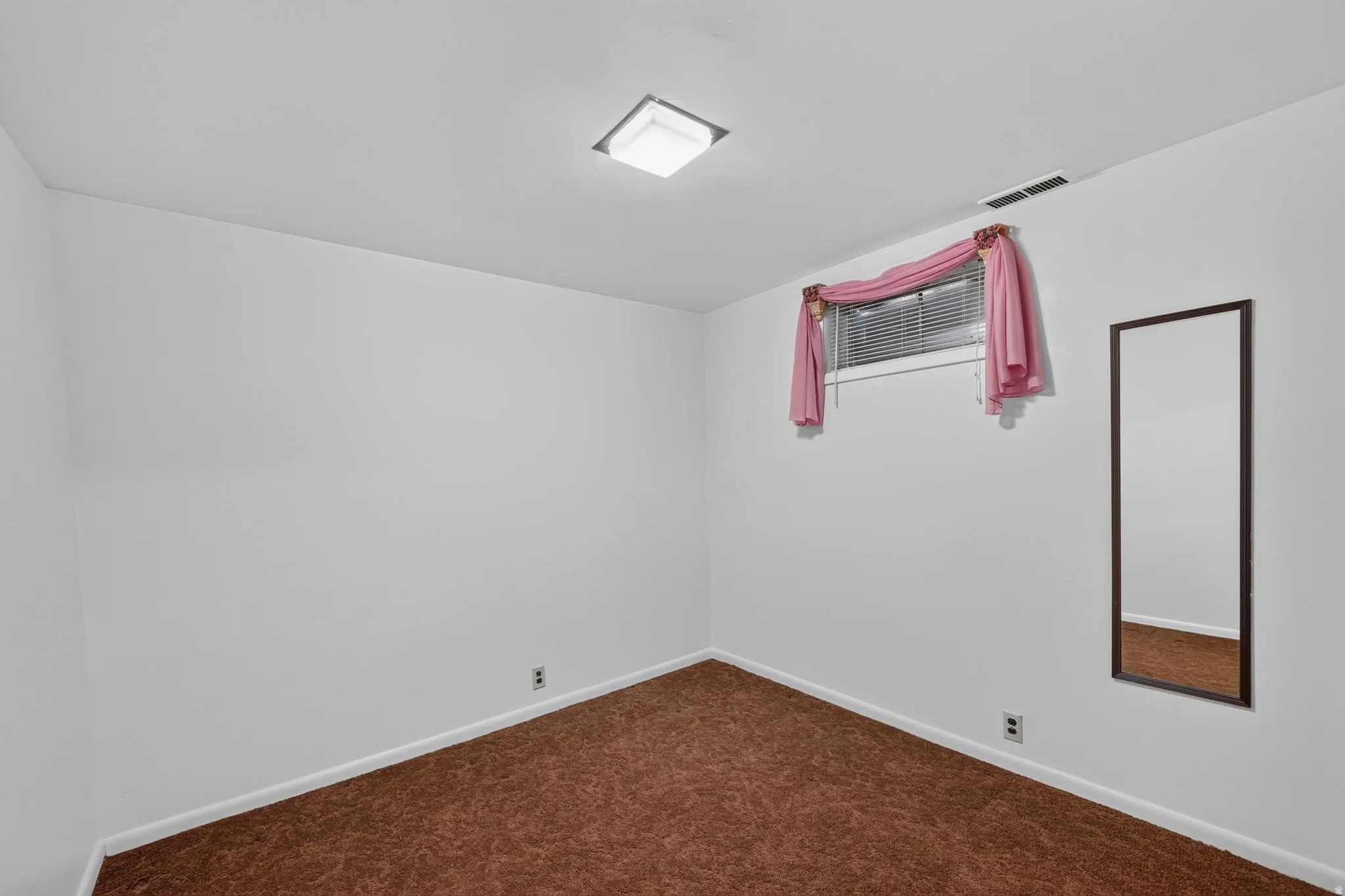 Room featuring brown carpeting, white walls, and a single window with blinds