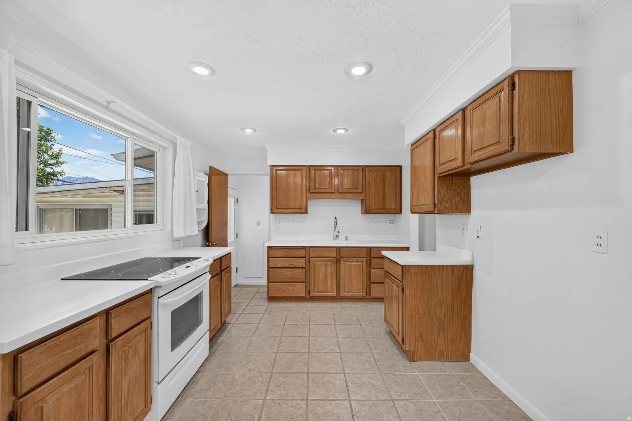 Kitchen featuring a white electric range, white countertops, wood-finish cabinetry, recessed lighting, and tile flooring