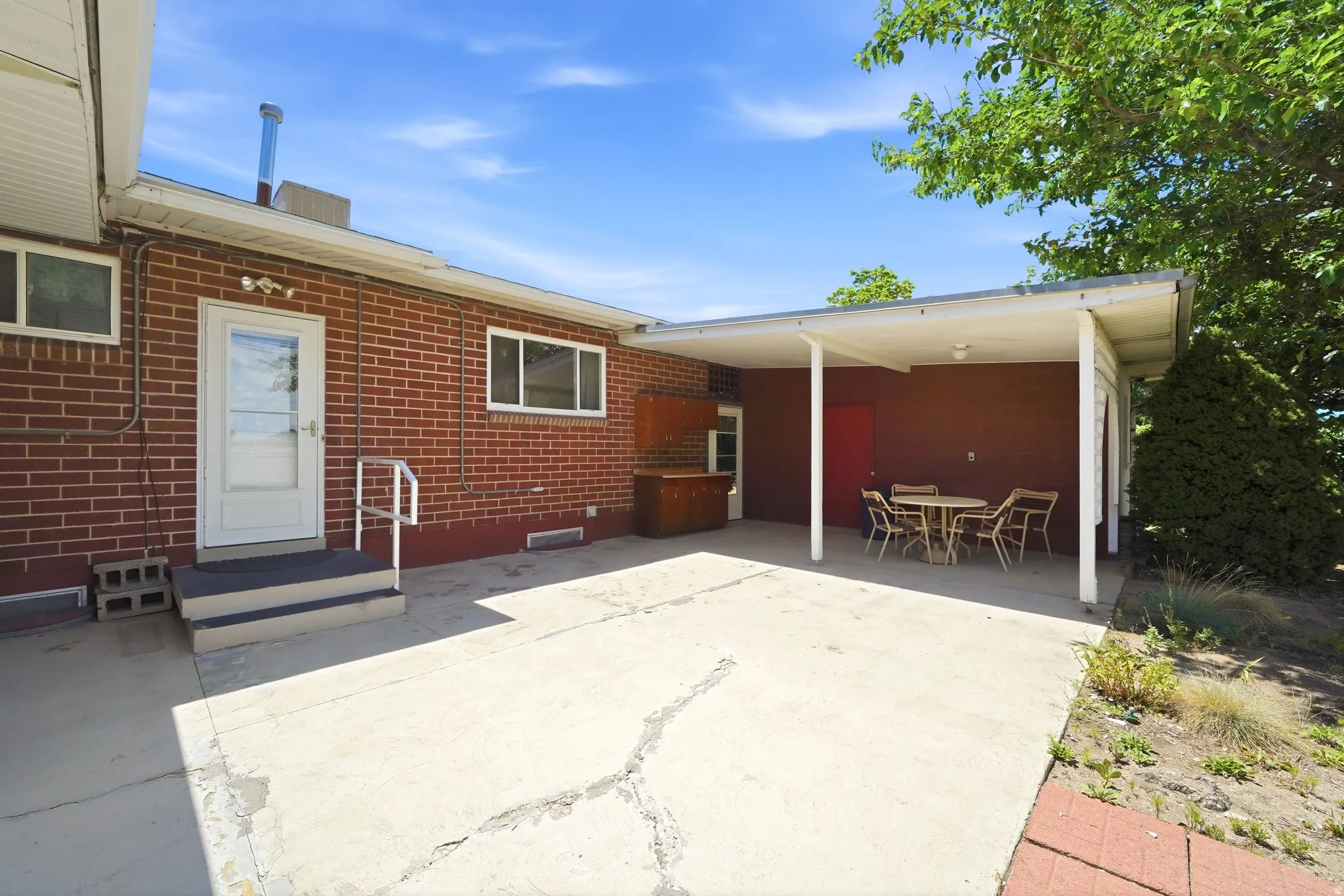 Red brick exterior featuring a white covered patio with concrete flooring