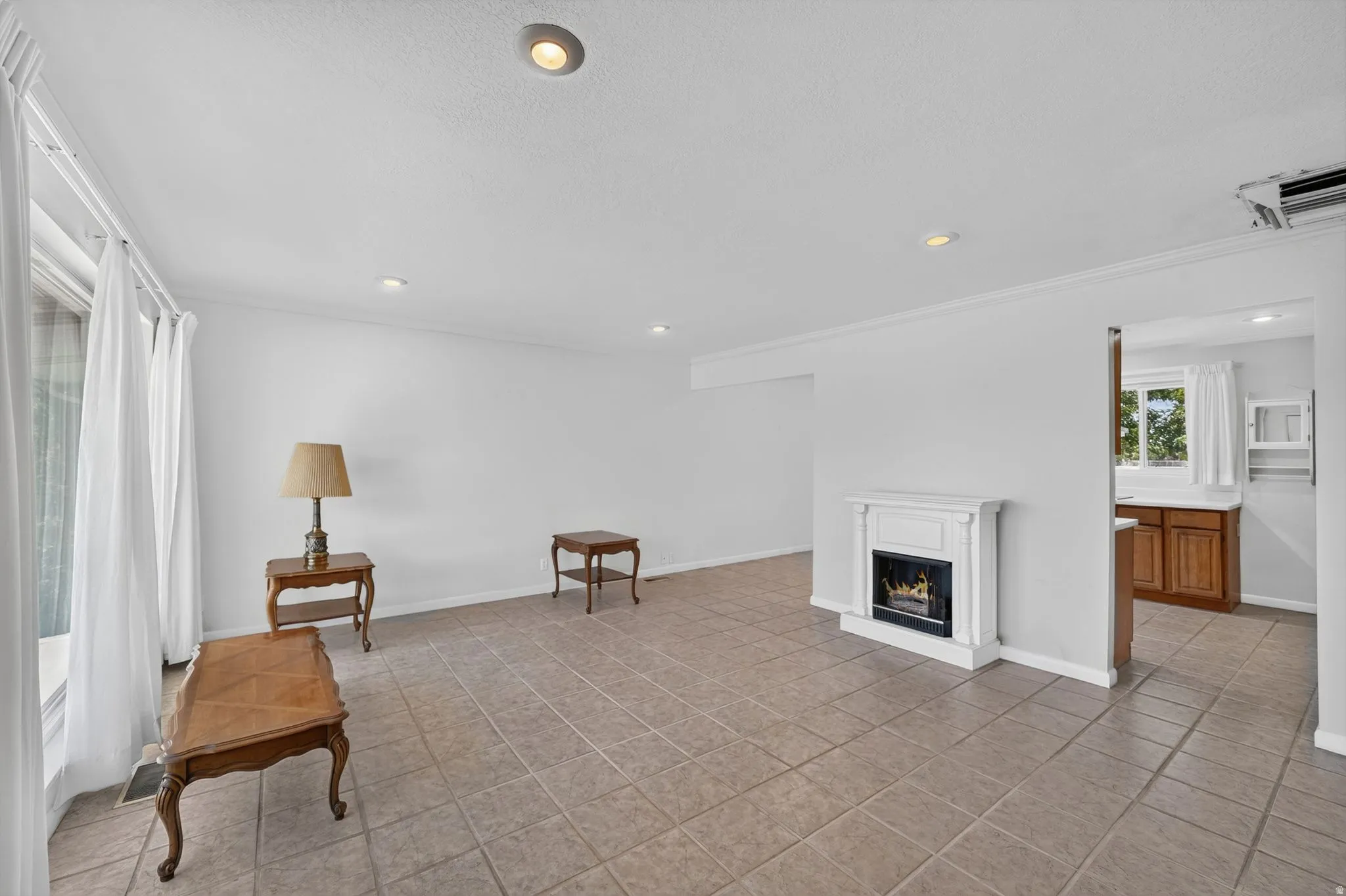 Spacious living area featuring neutral tile flooring, recessed lighting, and crown molding