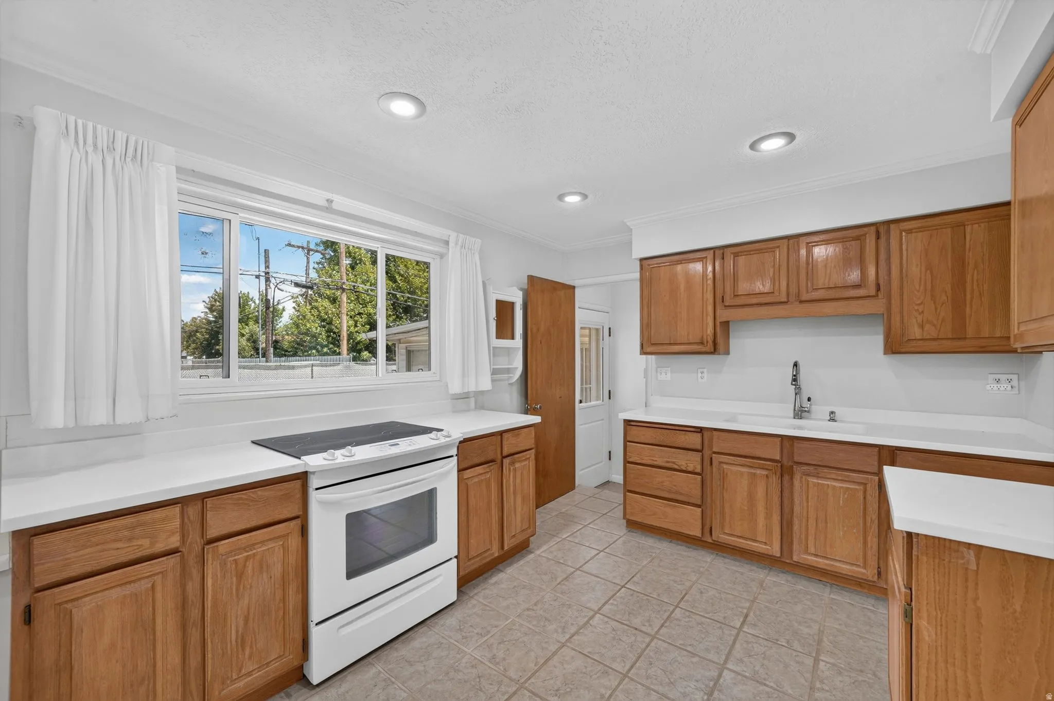 Kitchen featuring wood cabinetry, white countertops, a white electric range, and tile flooring
