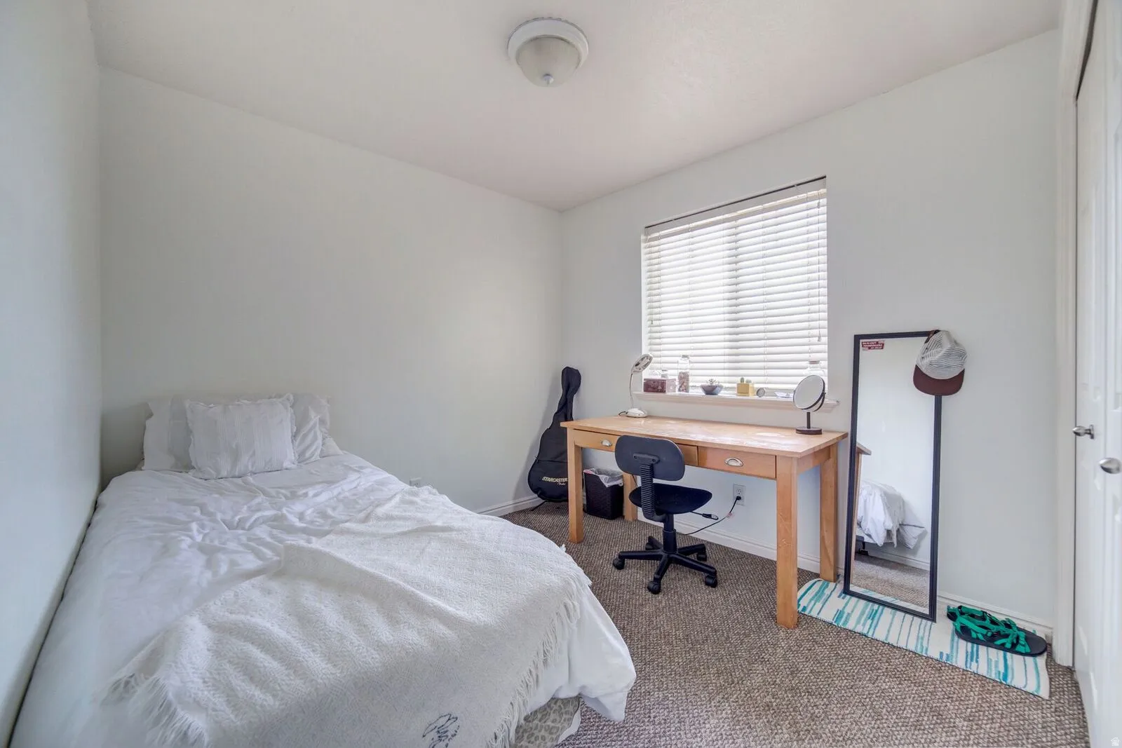 Carpeted room with a single window featuring horizontal blinds, a neutral wall color, and a flush-mount ceiling light fixture
