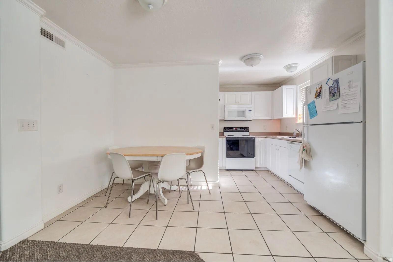 Kitchen and dining area featuring white cabinetry, white appliances, and tiled flooring