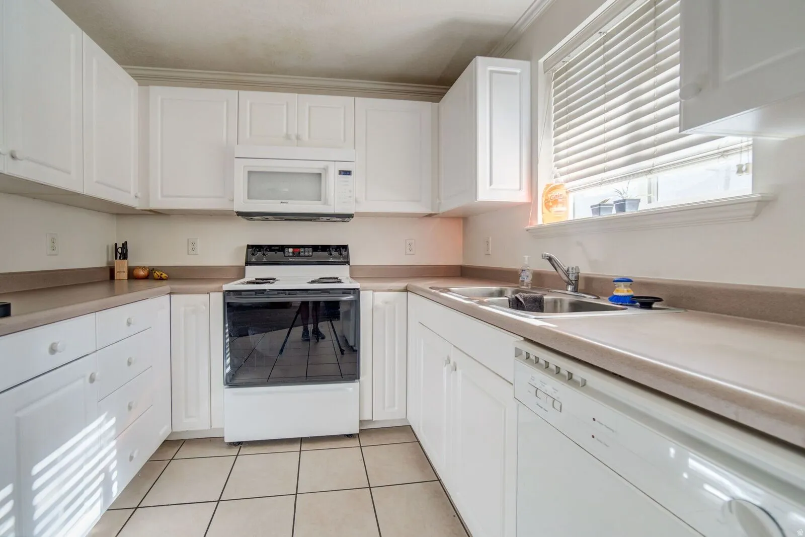 U-shaped kitchen featuring white cabinetry, light-toned countertops, and tile flooring