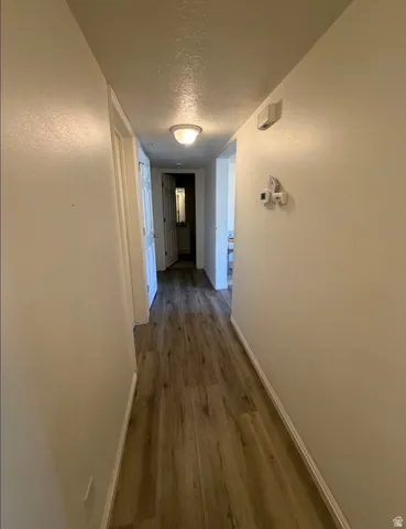 Hallway featuring wood-finish flooring and light-toned walls