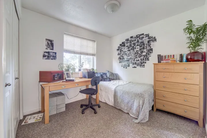 Bedroom featuring a window with horizontal blinds, carpet flooring, and a flush-mount ceiling light