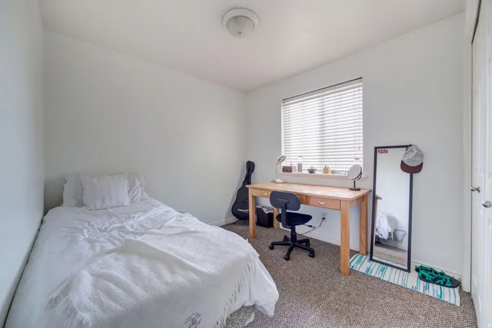 Carpeted room with a single window featuring horizontal blinds, a neutral wall color, and a flush-mount ceiling light fixture