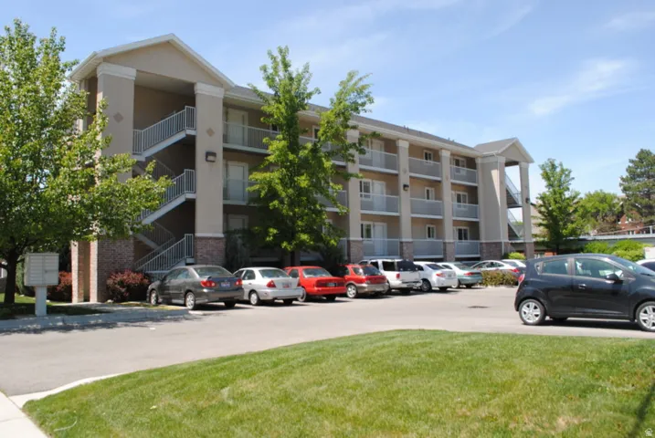 Multi-story building featuring stucco exterior with brick accents, private balconies, and external staircases