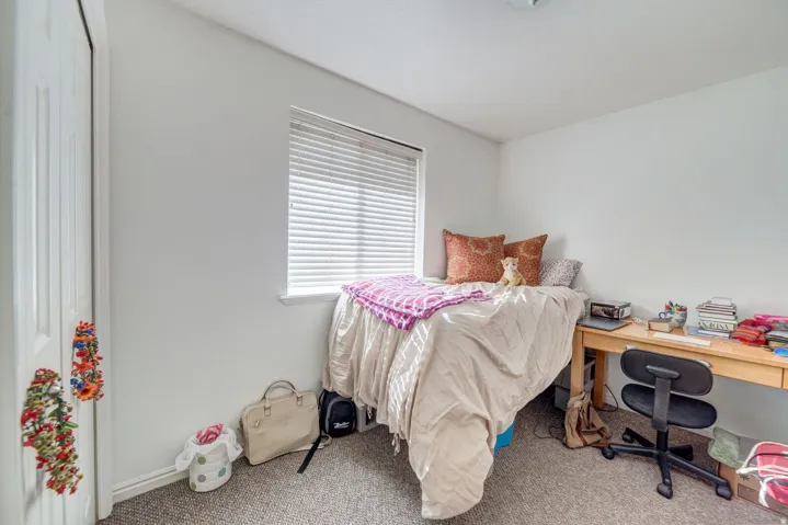 Bright room featuring a window with horizontal blinds, neutral wall paint, and gray carpet flooring