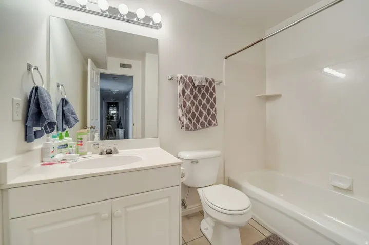 Full bathroom featuring a single vanity with storage, an integrated sink, a rectangular mirror, a four-light vanity fixture, and a combination tub and shower