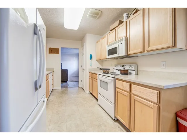 Kitchen featuring light wood cabinetry, white appliances, and a built-in microwave