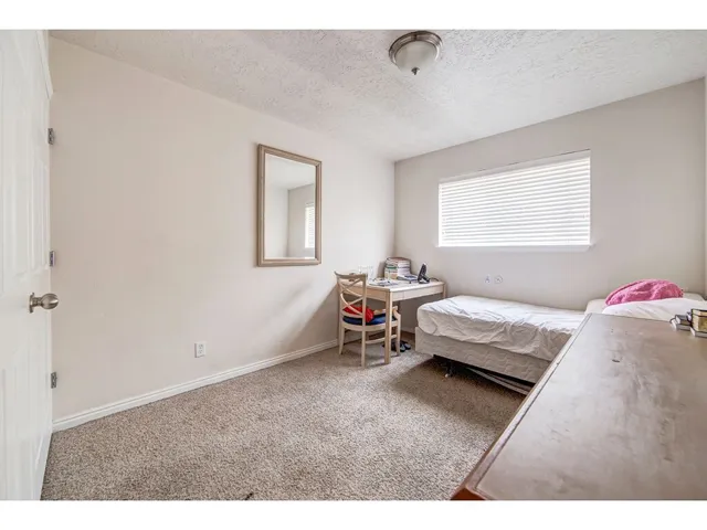 Bedroom featuring a neutral color palette, wall-to-wall carpeting, and a window with horizontal blinds