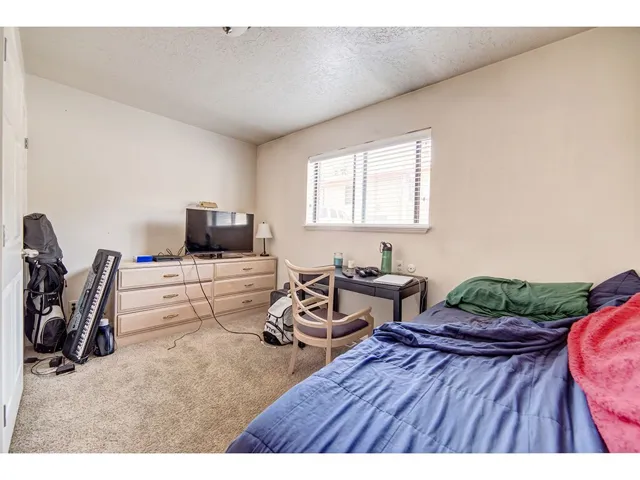 Interior room featuring a single window with blinds, neutral wall paint, and carpet flooring