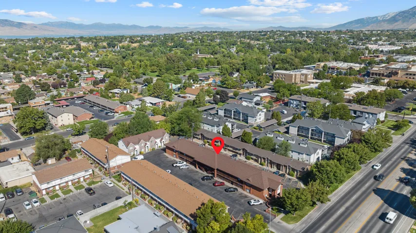 Aerial perspective showcasing multiple residential structures with brown roofing, extensive paved parking areas, and mature green landscaping