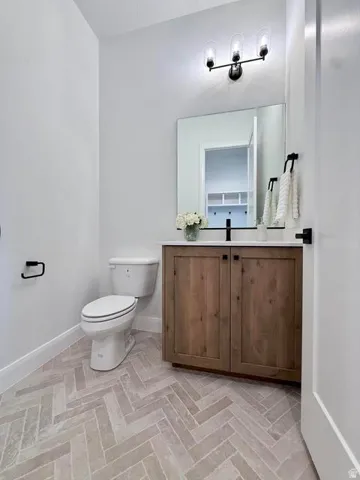 Bathroom featuring a wood-finish vanity with a black countertop, modern black fixtures, and a rectangular mirror