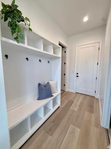 Entryway featuring a built-in white storage bench with cubbies, overhead shelving, and wall-mounted hooks