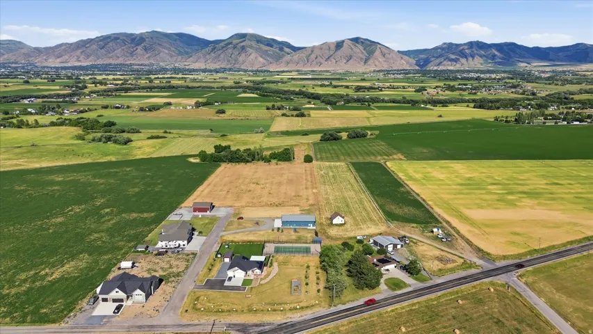 Expansive agricultural landscape featuring distant mountain ranges and several residential properties
