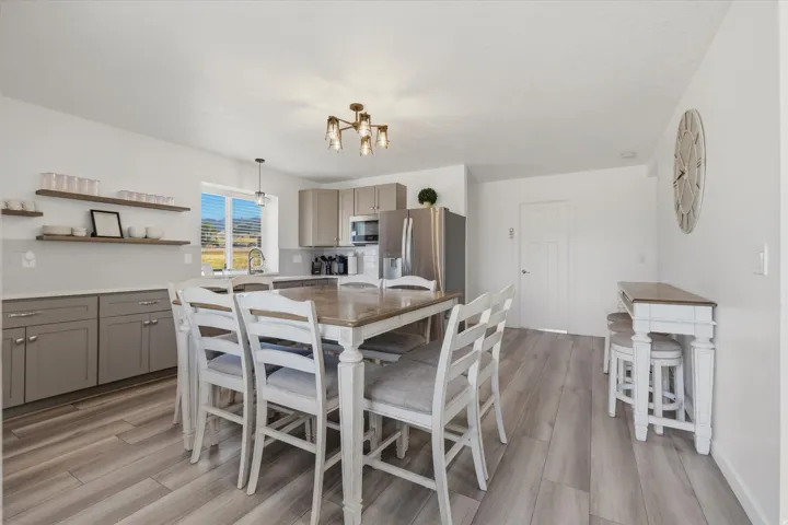Open concept kitchen featuring light wood-finish flooring, a white subway tile backsplash, and light gray cabinetry