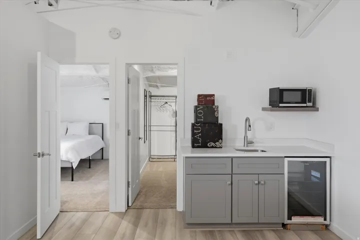 Compact kitchenette featuring gray cabinetry, a white countertop, a stainless steel sink, and a built-in beverage cooler