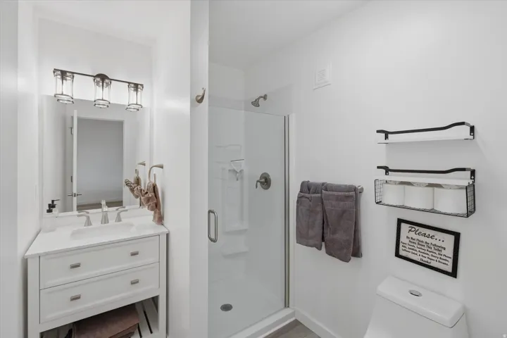 Full bathroom featuring a white vanity with a recessed sink, brushed nickel faucet, and a frameless mirror