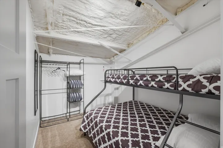 Room featuring an exposed beam ceiling with spray foam insulation, light-colored walls, and carpeting