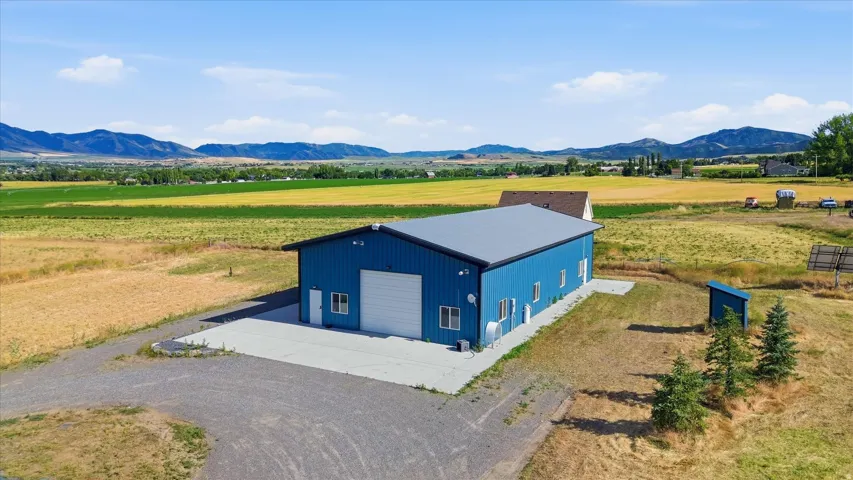 Blue metal-sided outbuilding with a gray roof and a large white garage door