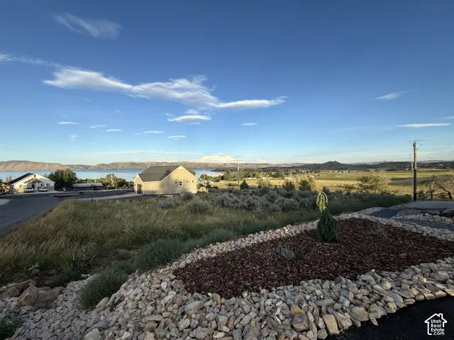 Expansive lot featuring native landscape, decorative stone ground cover, mulch beds, and prominent mountain and water scenery