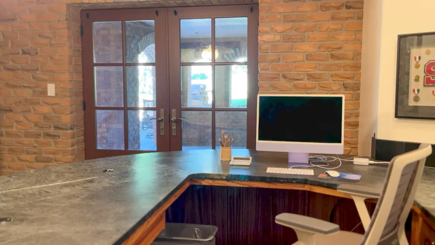 Built-in desk featuring a stone-finish countertop, wood-finish base, and exposed brick wall