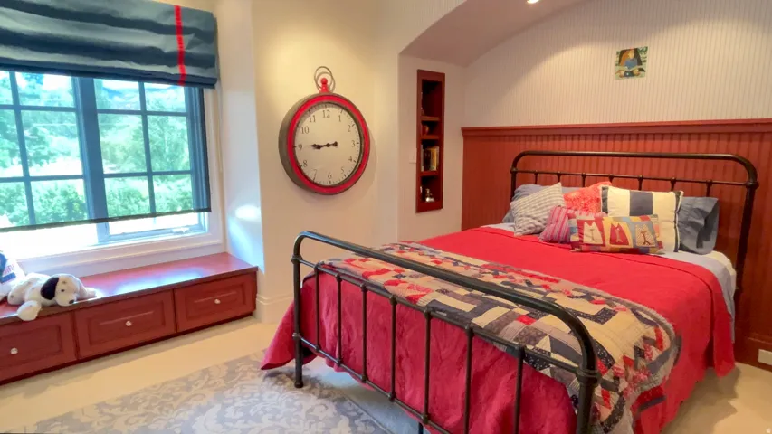Bedroom featuring beadboard wainscoting, a built-in window seat with storage, and a recessed shelving unit