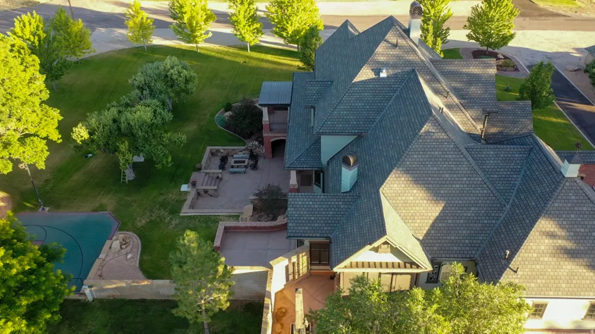 Extensive property featuring a multi-level roofline, a sport court, and a large patio area with built-in seating