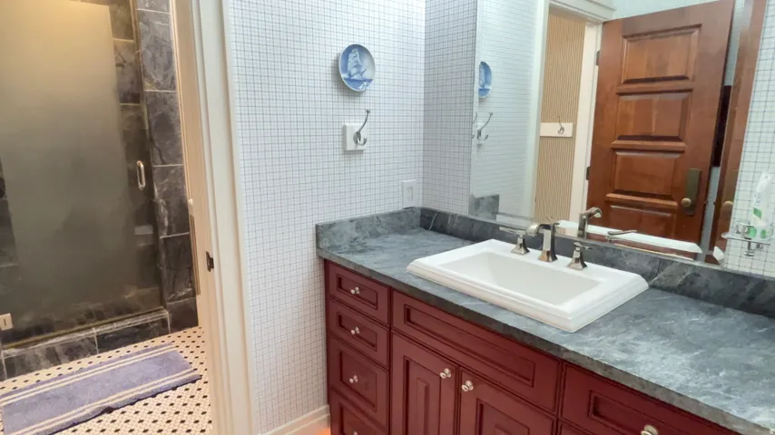 Bathroom vanity featuring a white undermount sink, dark countertop, and red wood-finish cabinetry with silver-tone hardware