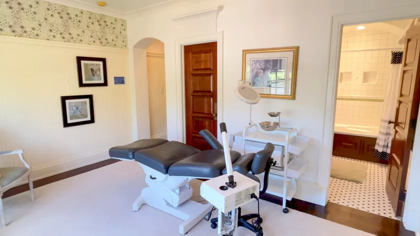 Archway entry to an interior room with white wainscoting and a patterned wall covering