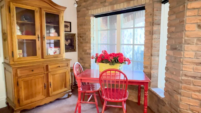 Bright dining nook featuring a large window with white muntins and brick wall details