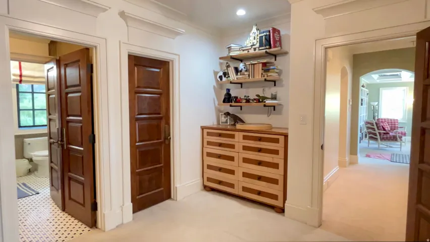 Hallway featuring architectural trim, multiple paneled doors, and built-in shelving with a base cabinet