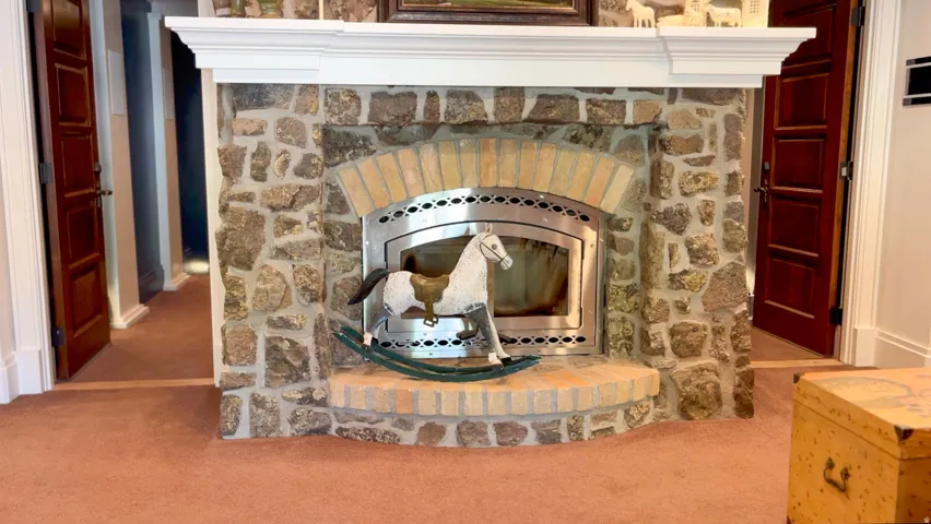 Stone-clad fireplace featuring a brick arch and stainless steel insert