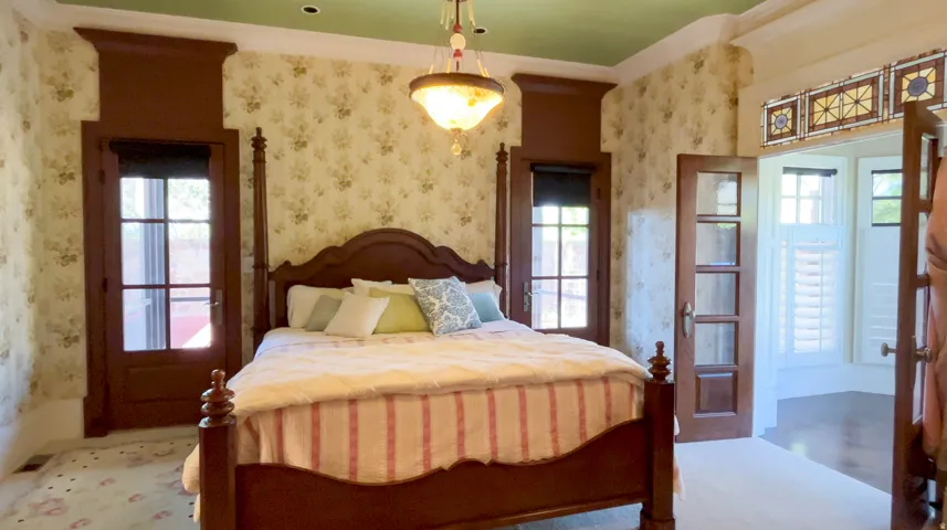 Hardwood floors and patterned wallpaper complement the green painted ceiling