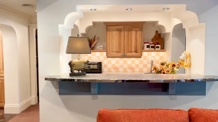 Built-in pass-through serving counter featuring a metal finish countertop and a checkered tile backsplash