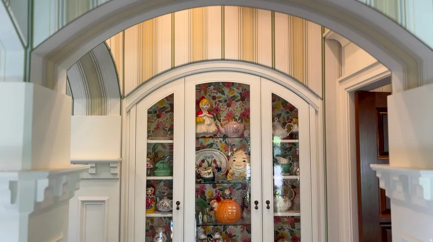 Archway framing a built-in display cabinet with arched glass doors
