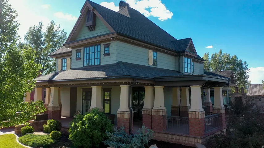 Two-story residence featuring a covered front porch with substantial columns, brick accents, and a dark railing