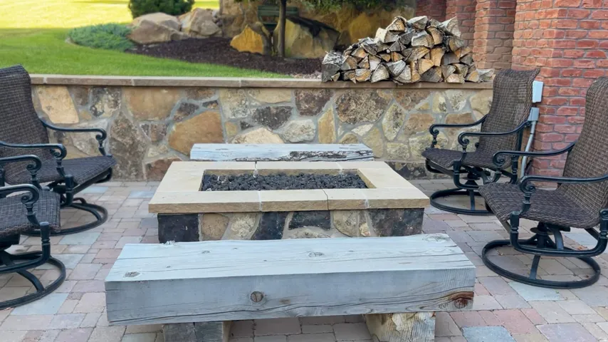 Outdoor patio featuring a stone fire pit with a light-colored capstone, surrounded by a paver surface