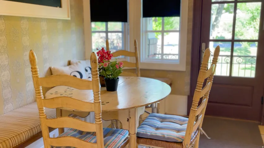 Breakfast nook featuring built-in bench seating with striped cushions, patterned wallpaper, double-pane windows, and an exterior door with glass panels