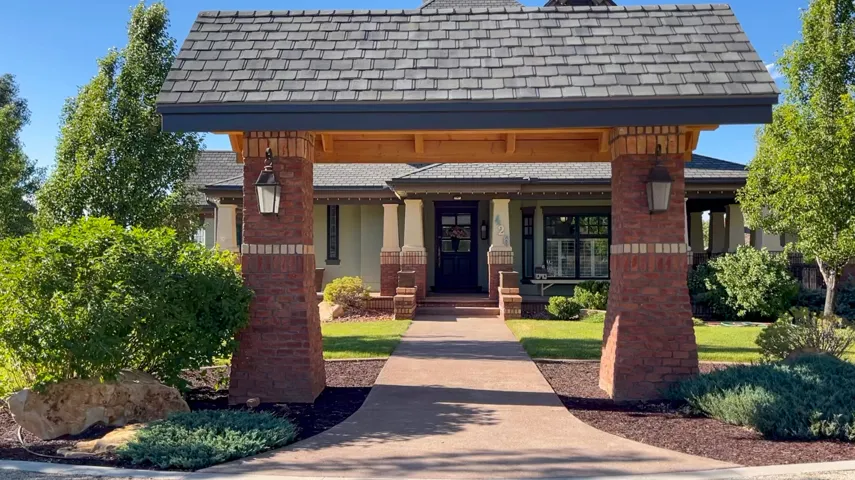 Arched entryway featuring brick pillars, decorative outdoor lighting, and a shake shingle roofline