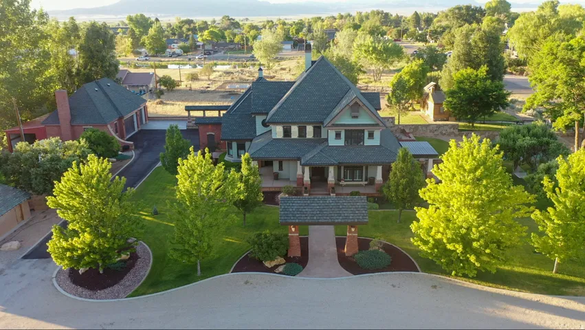 Gable-roof property featuring a multi-level exterior, extensive landscaping, mature trees, and a detached three-car garage