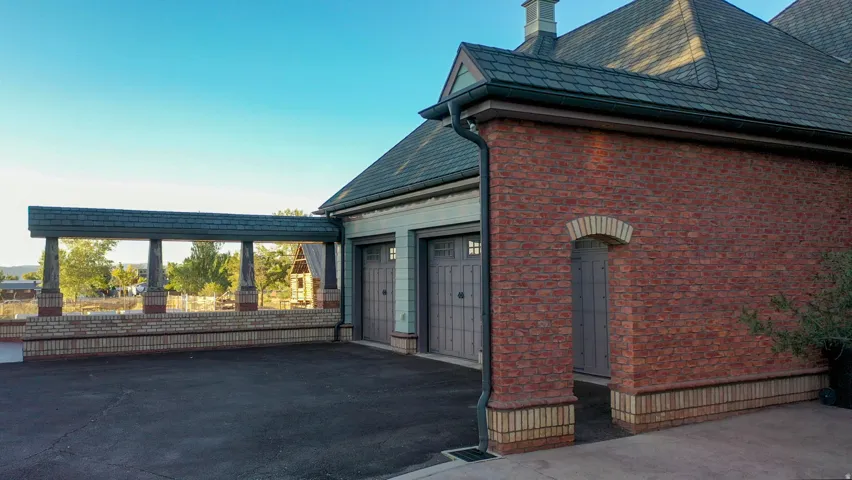Brick exterior with a dark roofline, featuring two garage doors and an arched entry