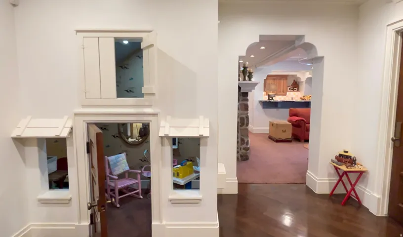 Hardwood-style flooring extends into an arched doorway featuring stone-clad columns