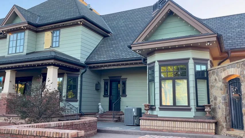 Exterior featuring a detailed bay window, stone wall with arched entry, multi-pane windows, and a dark shingle roof