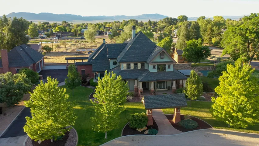 Grand residential estate featuring a multi-gabled roofline, brick and siding exterior, and a covered front porch